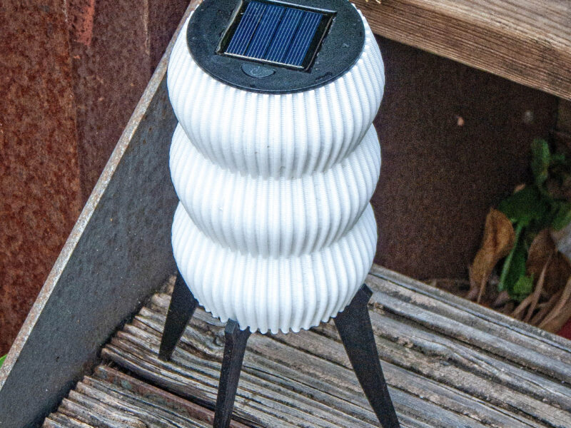 Lampe solaire de jardin "GUINGET" blanche imprimée en 3D en plastique recyclable, posée sur des marches en bois.
