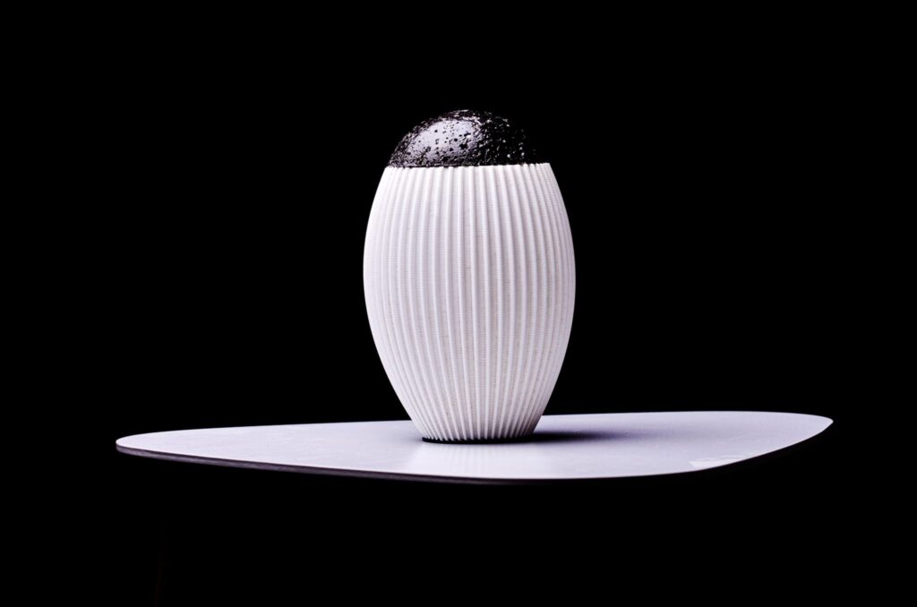 Sculpture lumineuse imprimée en 3D avec un socle en béton vernis, combinant des éléments blancs et noirs.