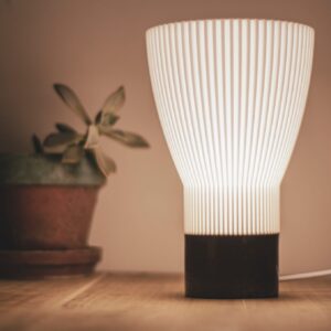 Lampe de table BLANCA allumée à côté d'une plante