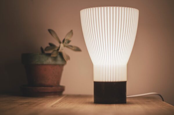 Lampe de table BLANCA allumée à côté d'une plante