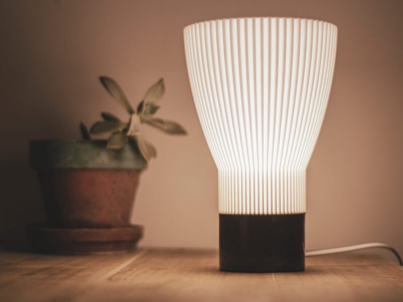 Lampe de table BLANCA allumée à côté d'une plante