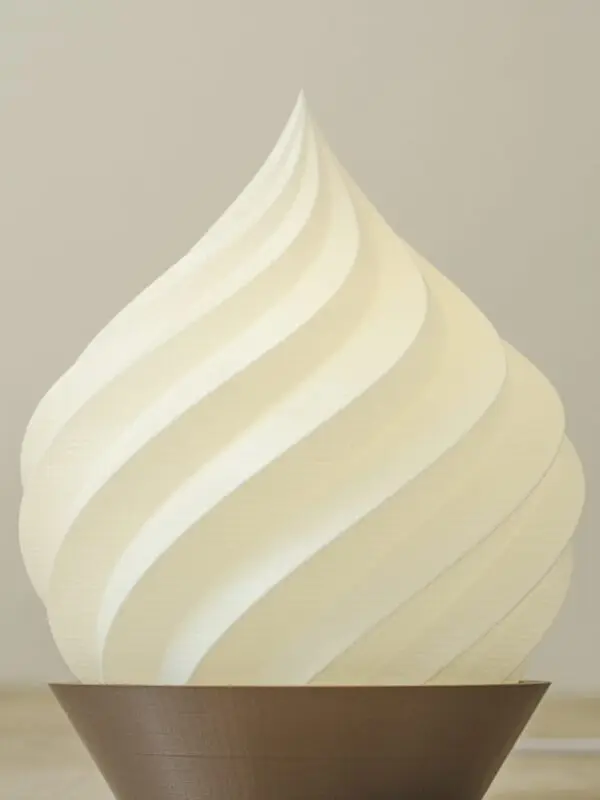 Lampe de table en forme de spirale blanche, imprimée en 3D avec une base marron.