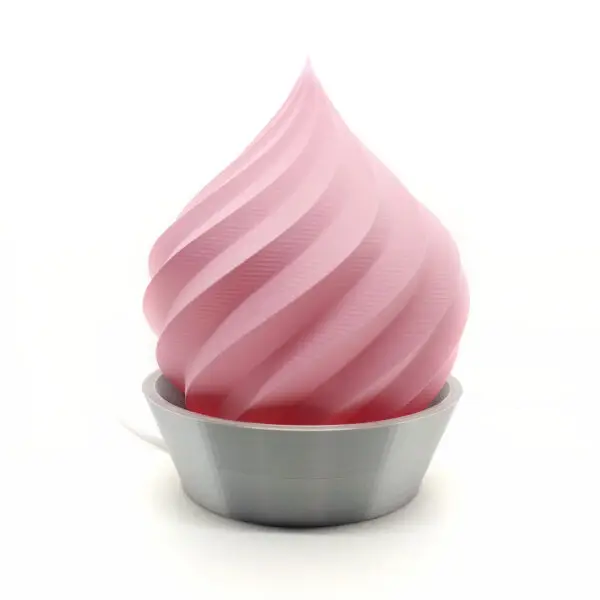Lampe de table en spirale rose, imprimée en 3D, avec une base métallique grise.