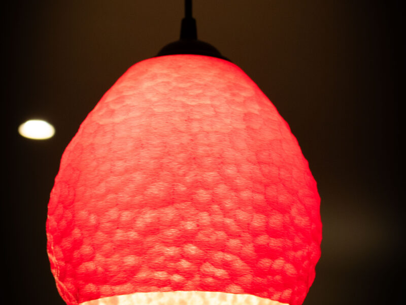 uspension lumineuse rouge imprimée en 3D avec un design sculpté.