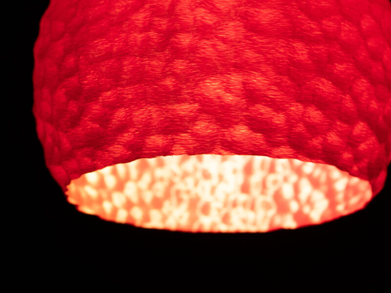 Gros plan sur une suspension lumineuse rouge imprimée en 3D avec une texture sculptée.