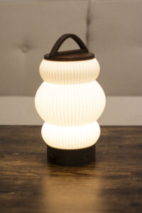 Lampe BUDO allumée, diffusant une lumière douce et chaleureuse avec un design moderne.