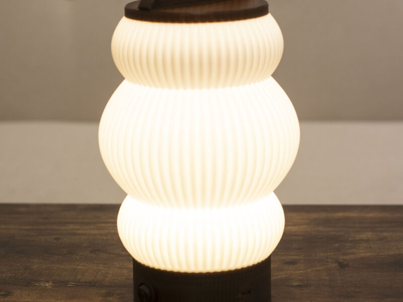 Lampe BUDO allumée, diffusant une lumière douce et chaleureuse avec un design moderne.