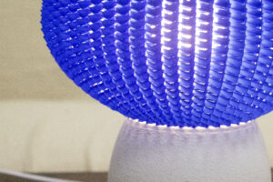 Détail d’une lampe design avec un abat-jour bleu texturé et une base blanche mate.