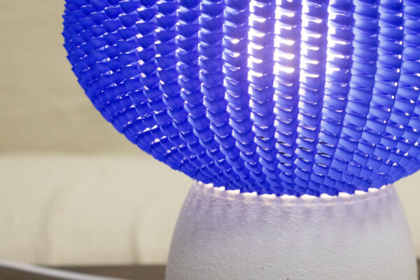 Détail d’une lampe design avec un abat-jour bleu texturé et une base blanche mate.