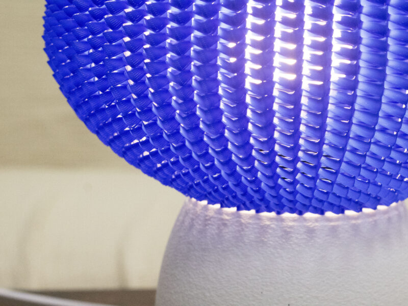 Détail d’une lampe design avec un abat-jour bleu texturé et une base blanche mate.