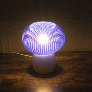 Lampe allumée avec abat-jour bleu texturé diffusant une lumière douce dans une pièce sombre.