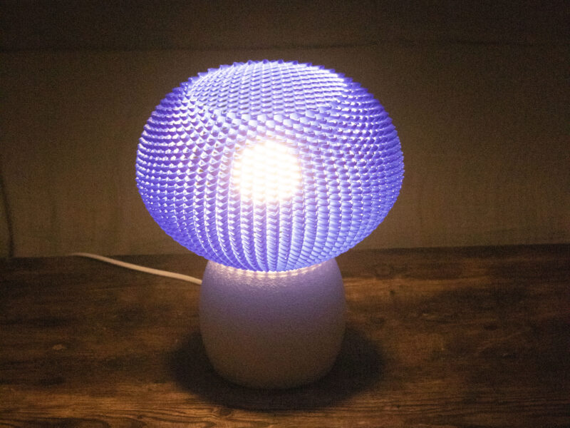 Lampe allumée avec abat-jour bleu texturé diffusant une lumière douce dans une pièce sombre.
