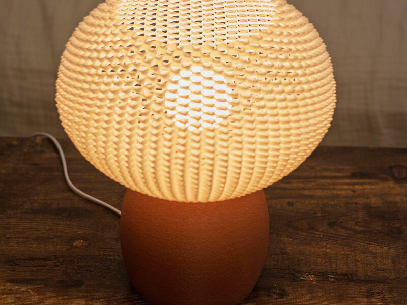 Lampe BULO en impression 3D avec un abat-jour ajouré blanc diffusant une lumière douce.