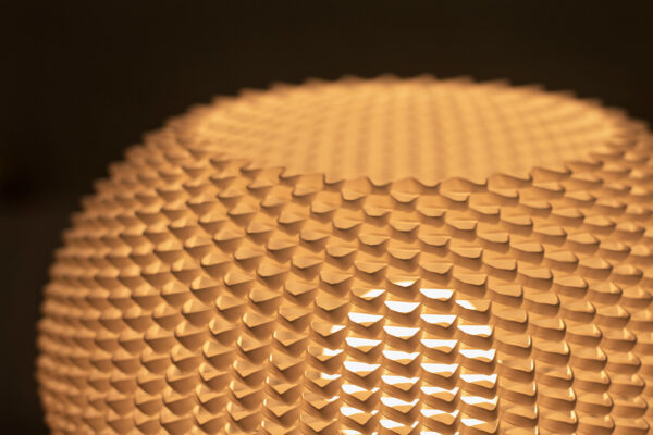 Gros plan sur l’abat-jour ajouré blanc de la lampe BULO, imprimé en 3D et diffusant une lumière douce.
