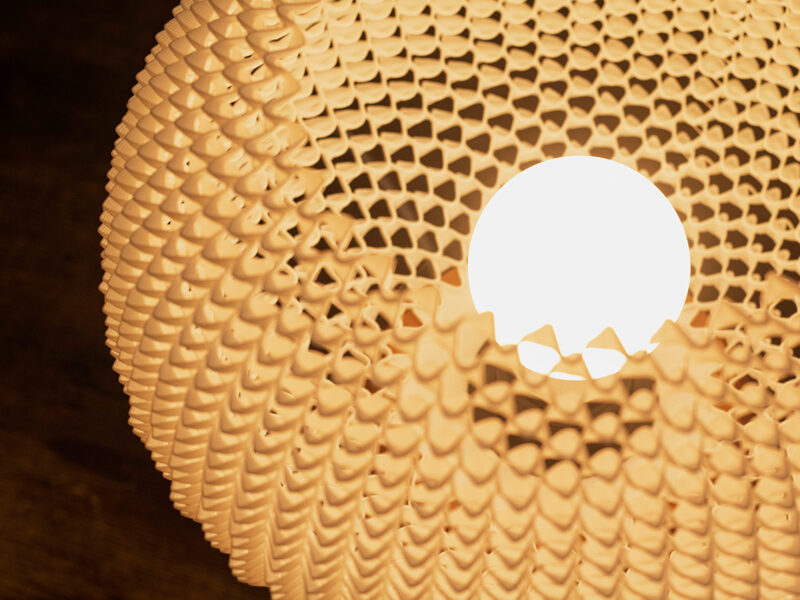 Vue rapprochée de l’intérieur de la lampe BULO, mettant en valeur son abat-jour ajouré imprimé en 3D et sa source lumineuse.
