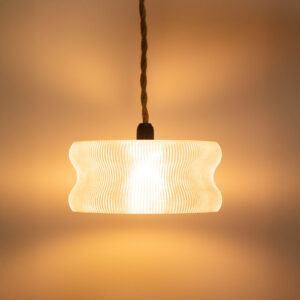 Suspension design en impression 3D avec un abat-jour transparent en forme de cloche ondulée diffusant une lumière chaude.